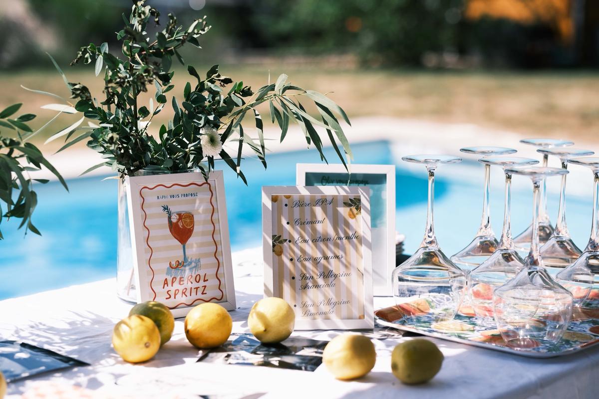 Cartes de boissons, citrons et verres sur une table au bord d’une piscine