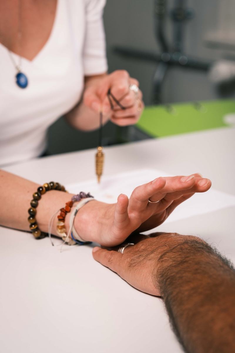 Deux mains et un pendule lors d’une séance à une table